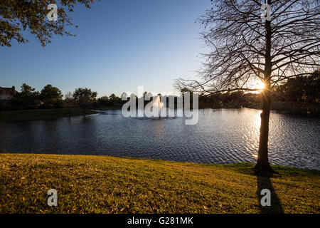 Sun impostazione su un lago residenziale circondata da case di lusso Foto Stock