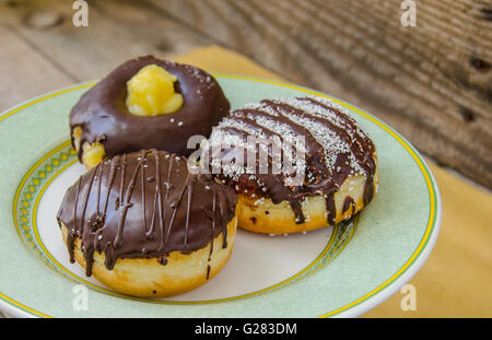 Ciambelle dolci su una piastra su un sfondo di legno Foto Stock