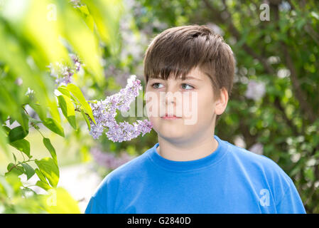 Ragazzo odorare un fiori lilla in posizione di parcheggio Foto Stock