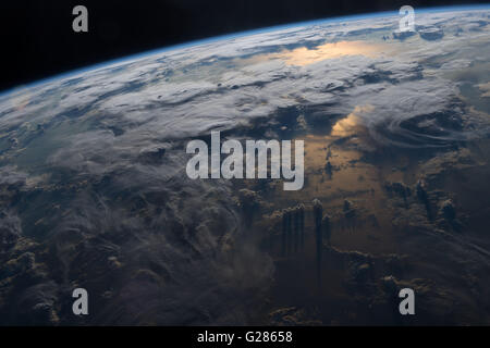 Vista di nuvole, temporali e tramonto riflesso off La Terra vista dalla stazione spaziale internazionale. Foto Stock