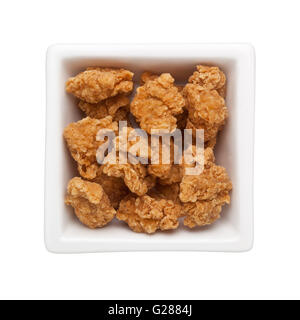 Fritte bite-size pollo in un recipiente quadrato isolato su sfondo bianco Foto Stock