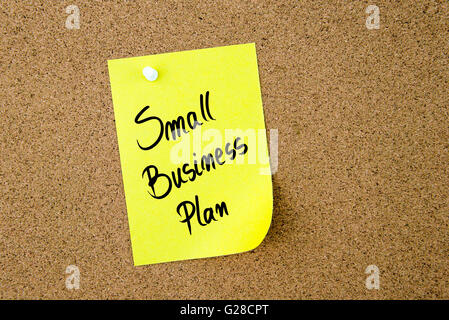 Small Business Plan scritto su carta gialla nota appuntata sulla bacheca di sughero con la puntina bianca, copia dello spazio disponibile Foto Stock