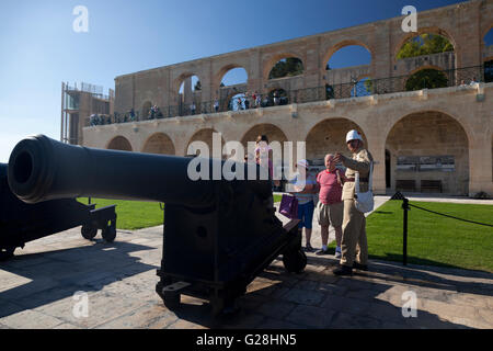 Una guida al sito di militari britannici fatiche mostra i turisti un ferro da stiro pistola SBBL 32 Pounder alla batteria a salve a La Valletta. Foto Stock