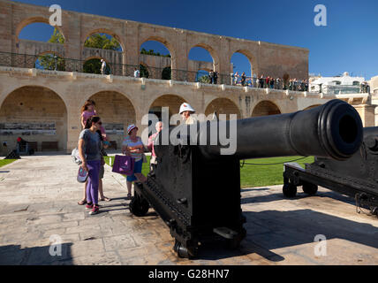 Una guida al sito di militari britannici fatiche mostra i turisti un ferro da stiro pistola SBBL 32 Pounder alla batteria a salve a La Valletta. Foto Stock