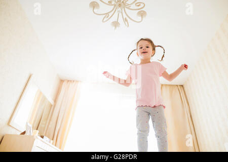 Carino bambina in camera da letto saltando su un letto Foto Stock