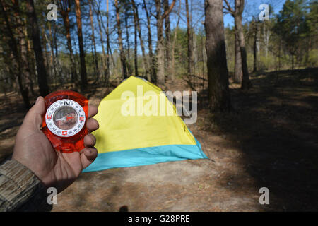 Orienteering nei boschi con una bussola. Compasso in mano sullo sfondo di turista tende. Foto Stock