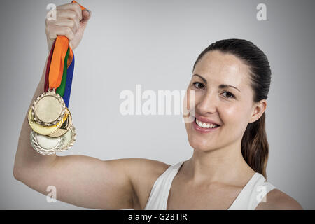 Immagine composita di atleta femminile in posa con medaglie d oro dopo la vittoria Foto Stock