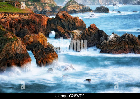 Bagliore di sera sul mare molte pile e archi di mare lungo la California's robusto Big Sur Costa. Foto Stock