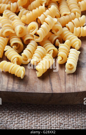 Pasta non cotta su di un tagliere di legno Foto Stock