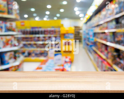 Tavola di legno tabella vuota nella parte anteriore del fondo sfocato. Prospettiva di legno chiaro su blur in giocattoli per bambini store - può essere utilizzato per d Foto Stock