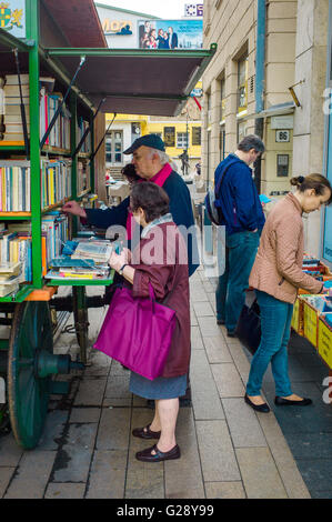 Persone studiano i titoli dei libri su un libro nel carrello Corvin köz, Budapest. Foto Stock