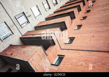 Abstract architettura urbana frammento, grigio e pareti in mattoni rossi con balconi e finestre Foto Stock