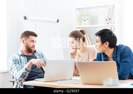 Tre gravi giovani imprenditori aventi un incontro di affari in ufficio Foto Stock