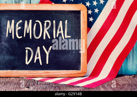 Il testo memorial day scritto in una lavagna e una bandiera degli Stati Uniti, su un rustico sfondo di legno Foto Stock
