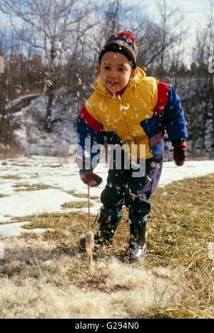 Giovane ragazzo giocando con cattails esplodere e baccelli di semi in inverno, Missouri, Stati Uniti d'America Foto Stock