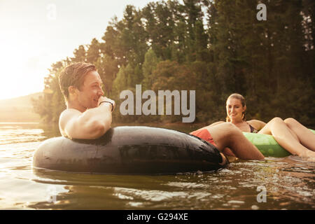 Ritratto di felice giovane nel lago su anello gonfiabile con la sua ragazza. Coppia giovane rilassante in acqua su un giorno d'estate. Foto Stock