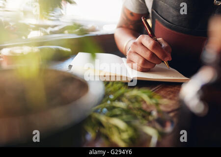 Immagine ritagliata di barman scrivere le idee per la creazione di nuovi cocktail. Foto Stock