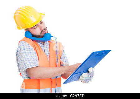 Occupato builder usando il telefono mentre si tiene negli appunti. Supporto o assistenza per la società di costruzioni Foto Stock