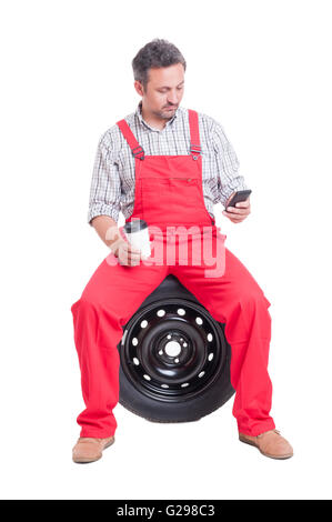 Meccanico automatico texting o la navigazione su smartphone nella pausa caffè Foto Stock