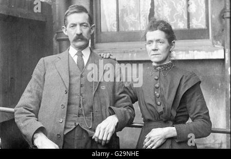 Inghilterra, 1927. Bianco e nero ritratto della coppia di mezza età che pongono, rivolta verso il visualizzatore. Uomo con i baffi, tuta, gilet e cravatta. Foto Stock