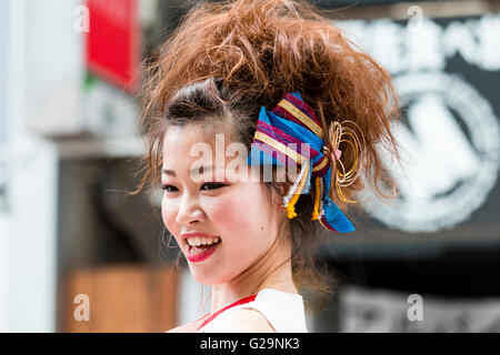Giappone Kumamoto. Hinokuni Yosakoi dance festival. Faccia colpo di sorridente giovane donna ballerina, con parrucca sulla parte superiore dei capelli normali e la prua sul lato di testa. Foto Stock