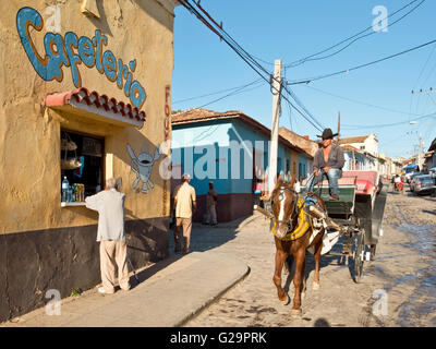 Strada tipica scena stradale nei pressi del centro di Trinidad, Cuba con un takeaway cafe, il ristorante e il turista a cavallo e carrello taxi. Foto Stock
