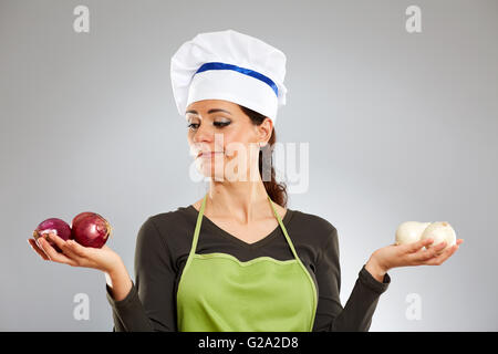 Indecisi cuoca scegliendo tra rosso e cipolle bianche Foto Stock