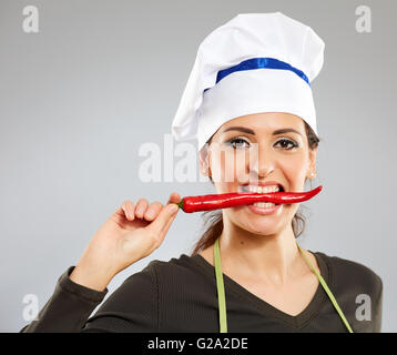 Donna attraente cucinare mordere un peperoncino piccante Foto Stock