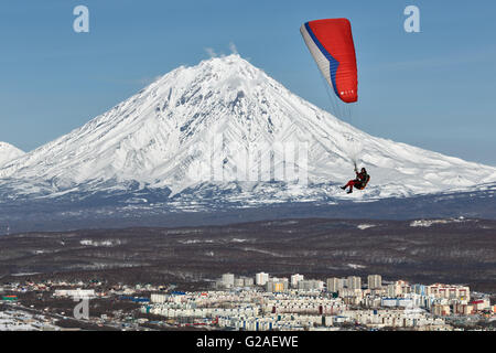 Parapendio volando sopra la città sullo sfondo del vulcano in una giornata di sole. Foto Stock