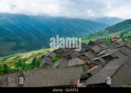 Riempito di acqua dei terrazzi di riso e della case di villaggio in montagna, Longsheng, provincia di Guangxi, Cina Foto Stock