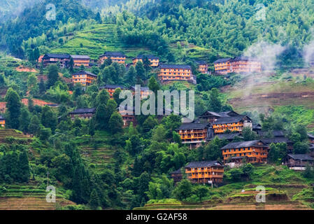 Case di villaggio e terrazze di riso nella nebbia di mattina in montagna, Dazhai, provincia di Guangxi, Cina Foto Stock