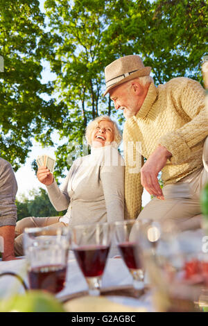 Felice personale senior giocando a carte in un giardino in estate Foto Stock