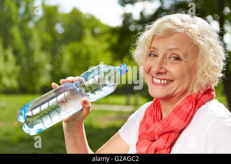 Sorridente donna senior di bere acqua fresca in estate Foto Stock