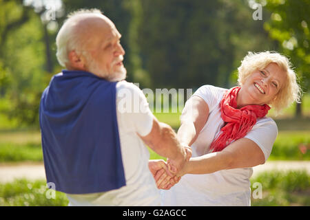 Il vecchio uomo e donna senior ballare insieme in un giardino in estate Foto Stock