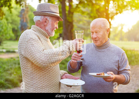 Due alti uomini ad una festa di compleanno tifo con un bicchiere di vino rosso Foto Stock