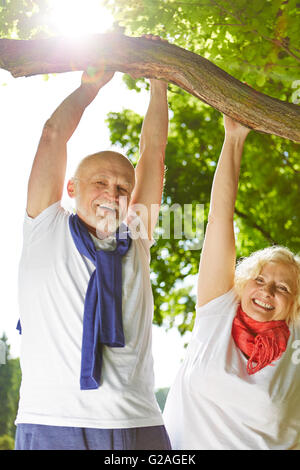 Il vecchio uomo e donna senior facendo sport nella natura appeso a un albero Foto Stock