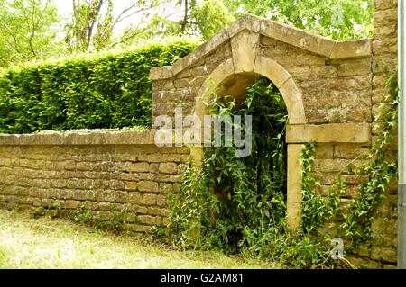 Vecchia entrata di pietre con un arco e una ringhiera in ferro. Foto Stock