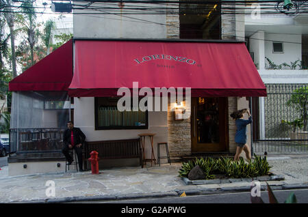 Giovane donna cammina davanti a Lorenzo ristorante bistro, scene di strada a Jardim Botanico quartiere, Rio de Janeiro, Brasile. Foto Stock
