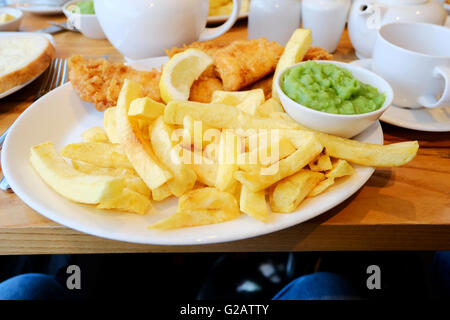 Un piatto di pesce inglese, trucioli e fiacco piselli servite su un piatto in un ristorante Foto Stock