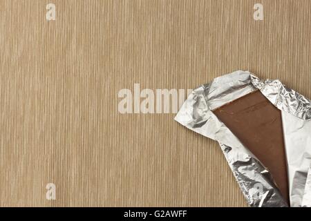 Il cioccolato avvolto in un foglio di alluminio sulla tovaglia luminoso. Pubblicità sul cioccolato. Il cioccolato di vendita . Il cioccolato di imballaggio Foto Stock