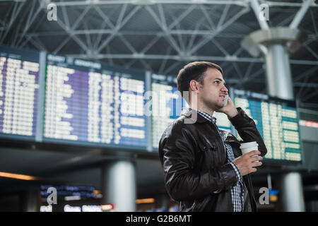 Sorridente giovane viaggiatore uomo all'aeroporto parlando al telefono nella parte anteriore della scheda calendario Foto Stock