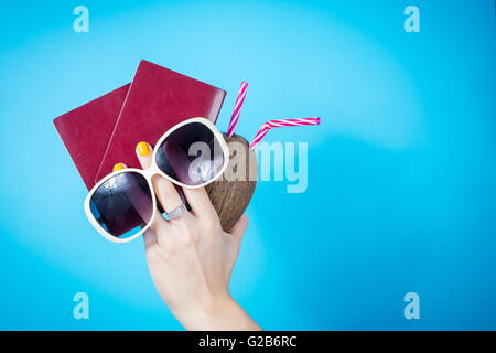 Mano Womans tenendo un due passaporti e accessori estate contro sfondo blu Foto Stock