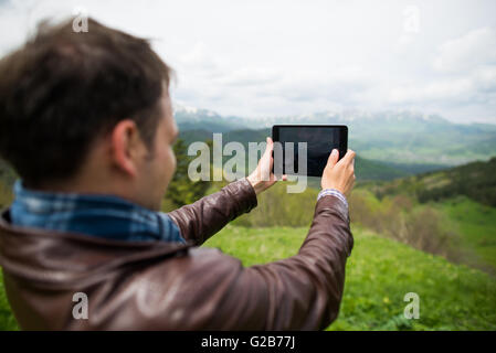Giovane uomo prendendo selfie foto con fotocamera tablet le montagne Foto Stock