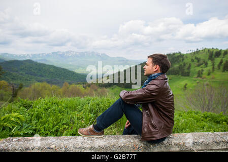 Escursionista maschio rilassante sulla cima di una montagna Foto Stock
