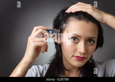 Close-up colpo di testa di un business donna tenendo un memory stick per collegarlo al lato della sua testa, shot su un backgro grigio Foto Stock