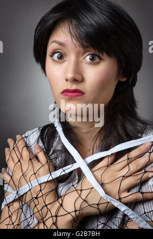 Close up studio shot di un giovane modello di business avvolto in una rete. Foto Stock