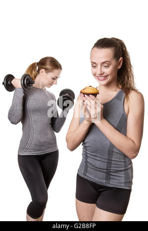 Due donne sportive azienda muffin e manubri su sfondo bianco Foto Stock