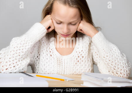 Ritratto di sottolineato bella ragazza casual, seduti alla scrivania, tenendo la testa in armi con esaurito frustrato expression Foto Stock