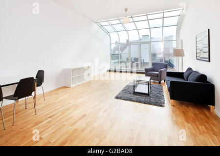 Conversione di Dach o soppalco in Reichenberger Strasse, Kreuzberg. Aprire il piano mansarda zona soggiorno con tavolo da pranzo. Arredamento moderno e un decor essenziale. Soffitto curvo per le finestre in vetro. Foto Stock