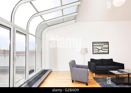 Conversione di Dach o soppalco in Reichenberger Strasse, Kreuzberg. Elegante e moderna area salotto. Curvato finestre da pavimento a soffitto. Pavimenti in legno e pareti bianche. Foto Stock